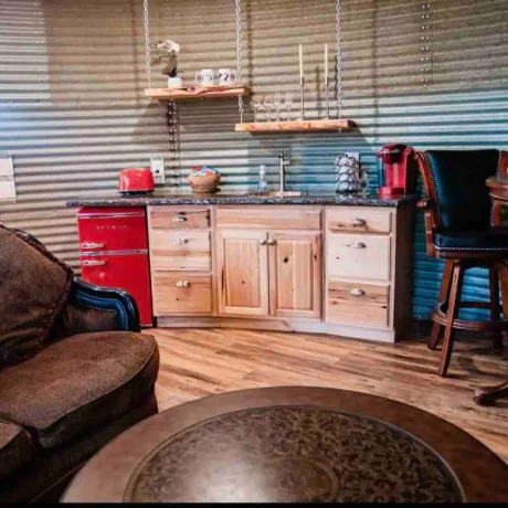 A cozy, wooden cabin nestled in a scenic setting with the sun setting behind it, emphasizing the rustic charm and peaceful atmosphere at Oak Meadow Ranch RV in Valley View, TX.