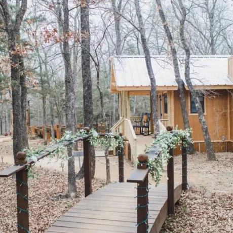 A cozy, wooden cabin nestled in a scenic setting with the sun setting behind it, emphasizing the rustic charm and peaceful atmosphere at Oak Meadow Ranch RV in Valley View, TX.