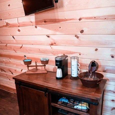 A cozy, wooden cabin nestled in a scenic setting with the sun setting behind it, emphasizing the rustic charm and peaceful atmosphere at Oak Meadow Ranch RV in Valley View, TX.