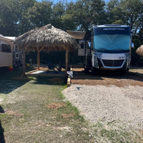 Picturesque RV sites nestled among shady oak trees with tranquil, spacious surroundings, fire pits, and picnic tables at Oak Meadow Ranch in Valley View, TX.